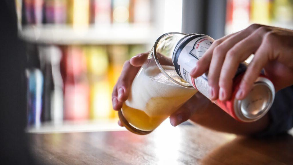 can of beer being poured into glass